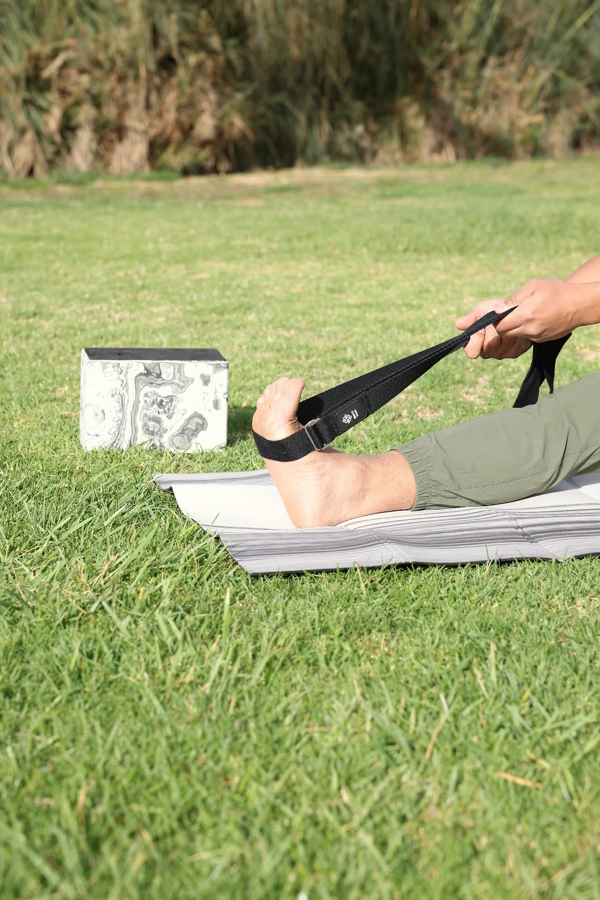A practitioner stretching with the Bento Yoga strap outdoors