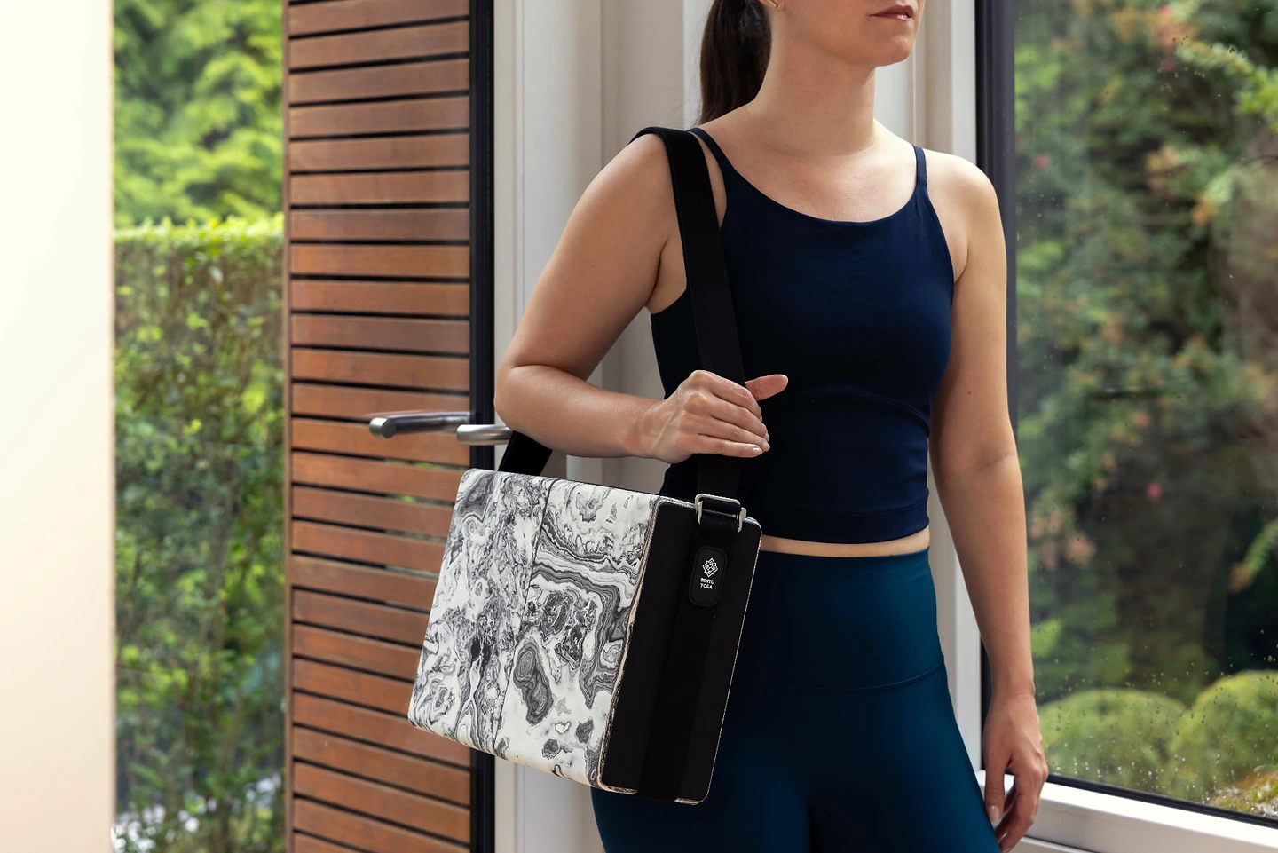 A practitioner carrying Bento Yoga ONE over her shoulder at the doorway